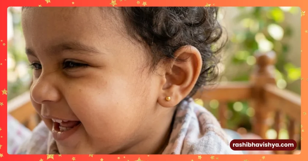 ಕಿವಿಗೆ ಚಿನ್ನದ ಓಲೆ ಧರಿಸಿ ನಗುತ್ತಿರುವ ಮುದ್ದಾದ ಮಗು.